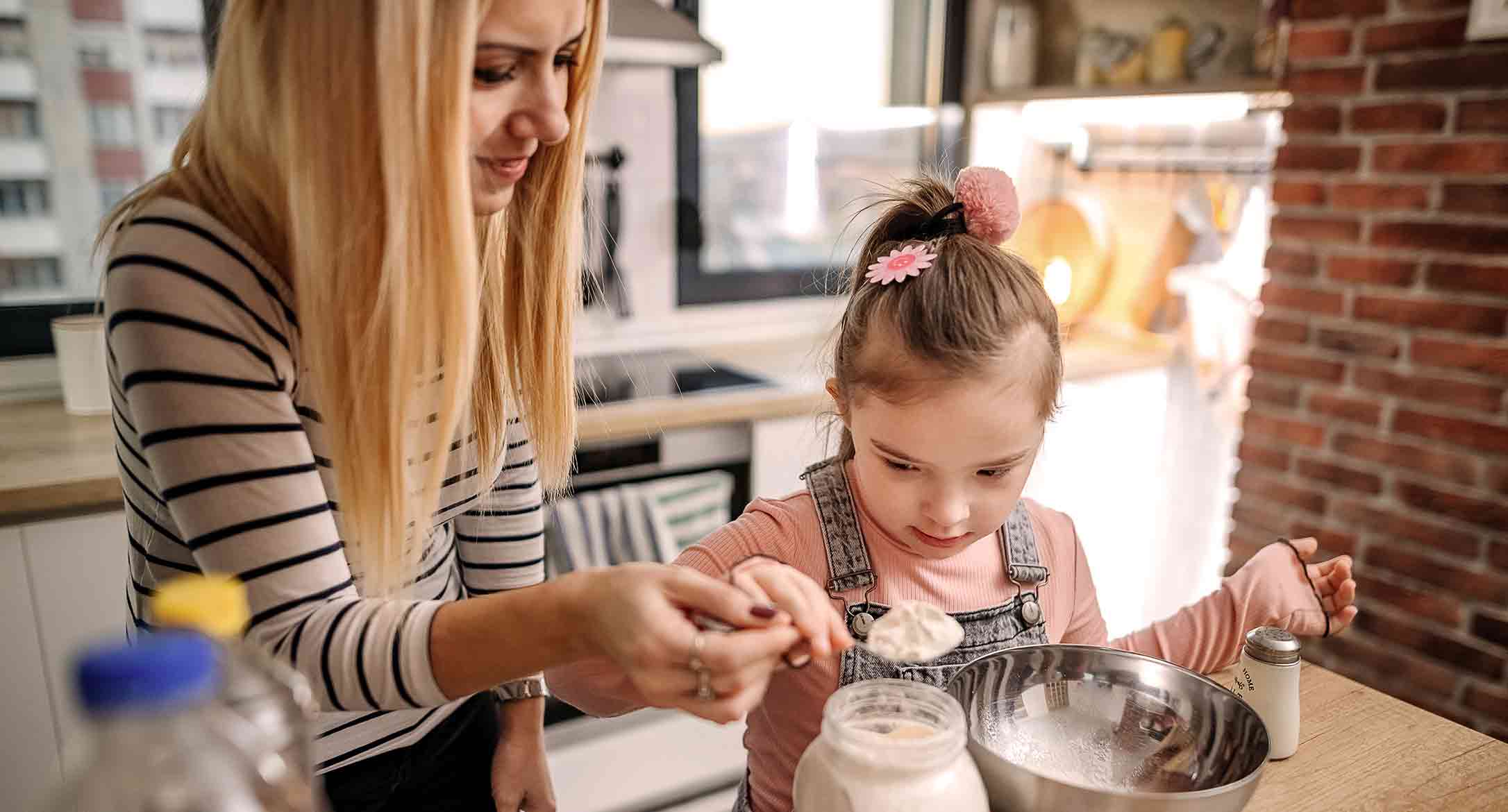 Une fillette et sa mère cuisinant ensemble.